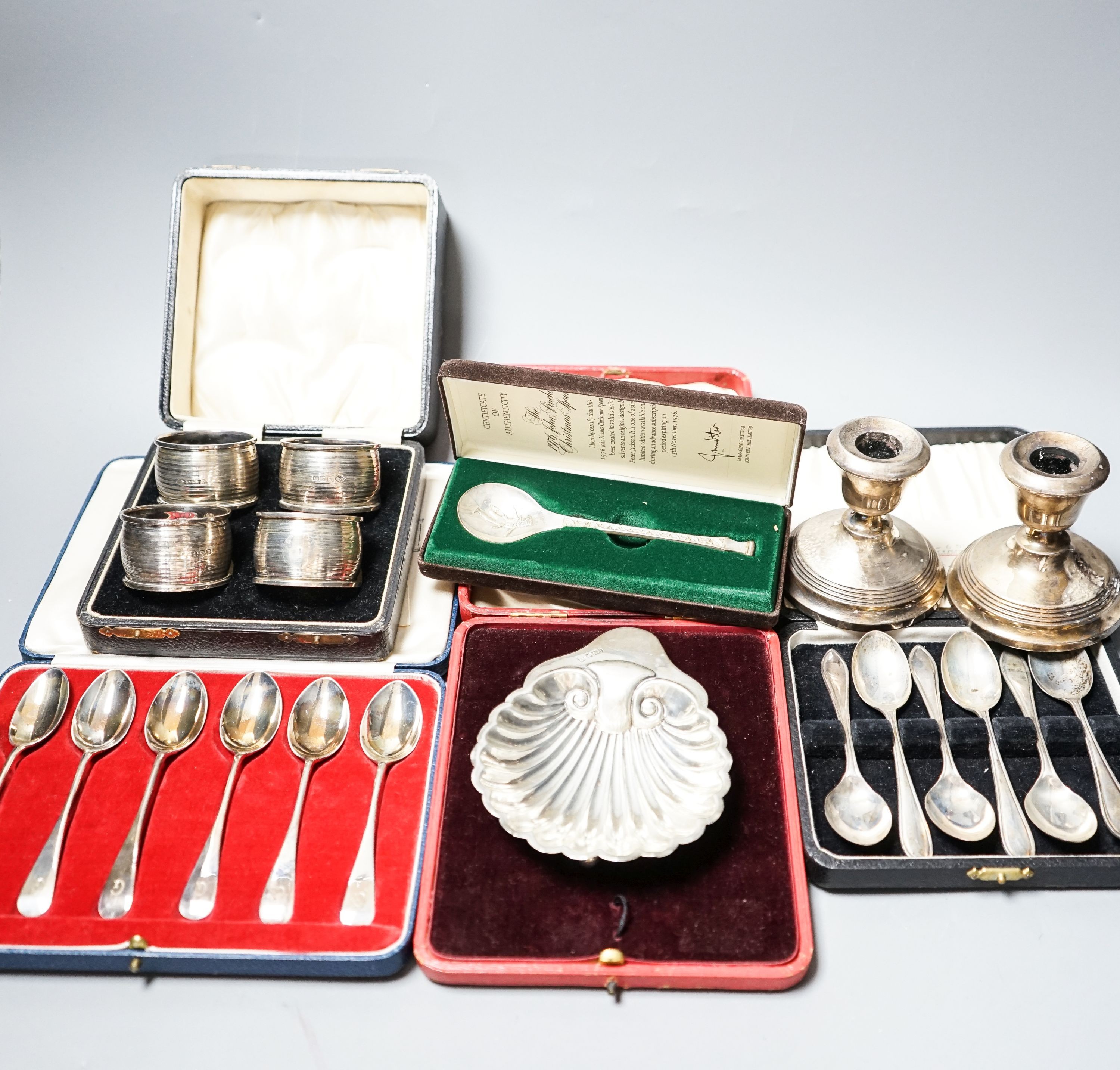 A cased pair of four 1920's silver napkin rings, four other cased items including butter shell and a pair of silver mounted dwarf candlesticks.